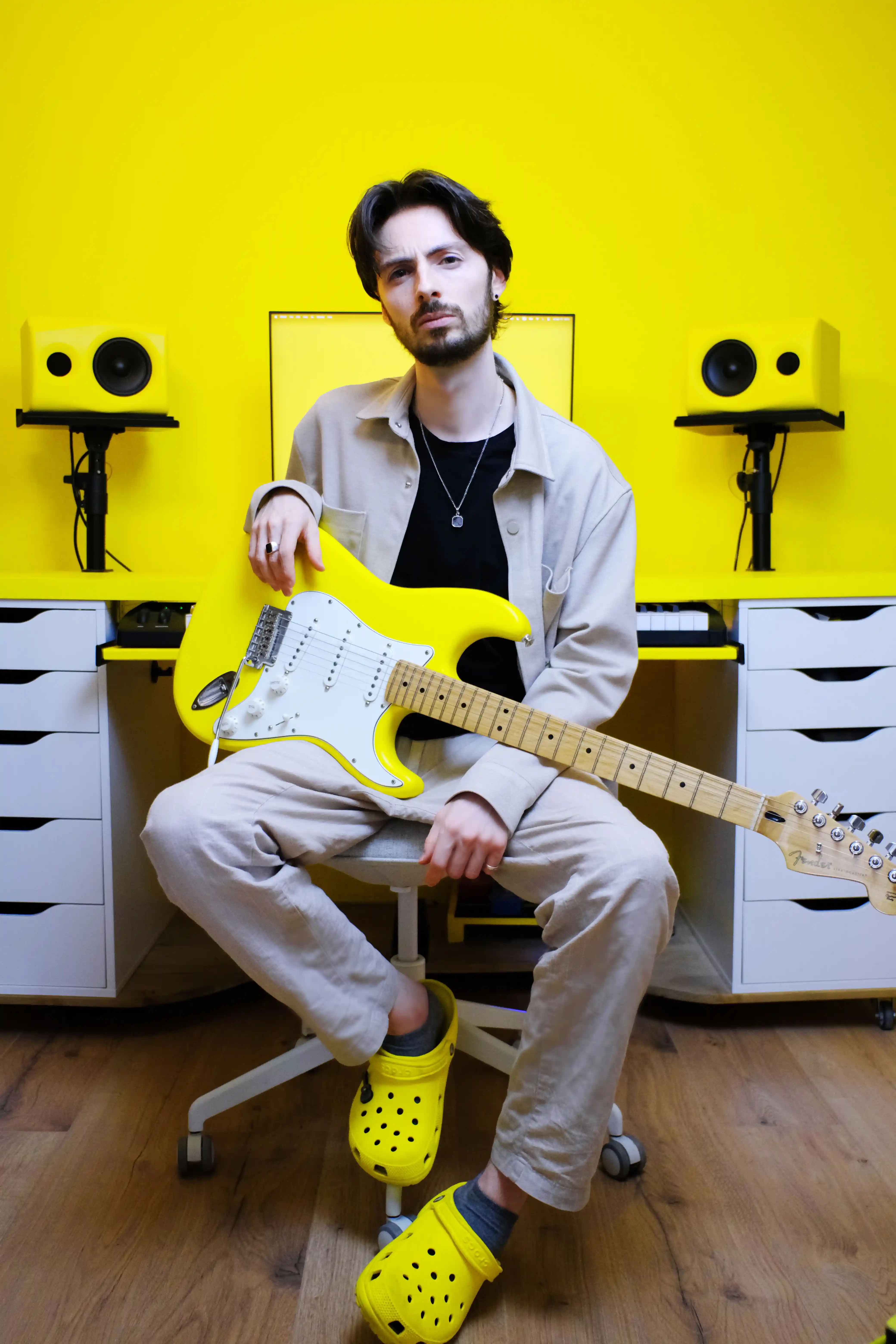 Producer sitting with a yellow electric guitar in the studio